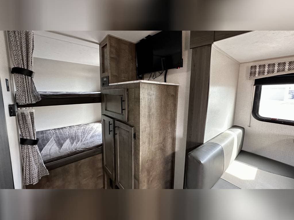 RV rental interior: comfy bunk beds, TV, and a dinette area for family meals and relaxation.