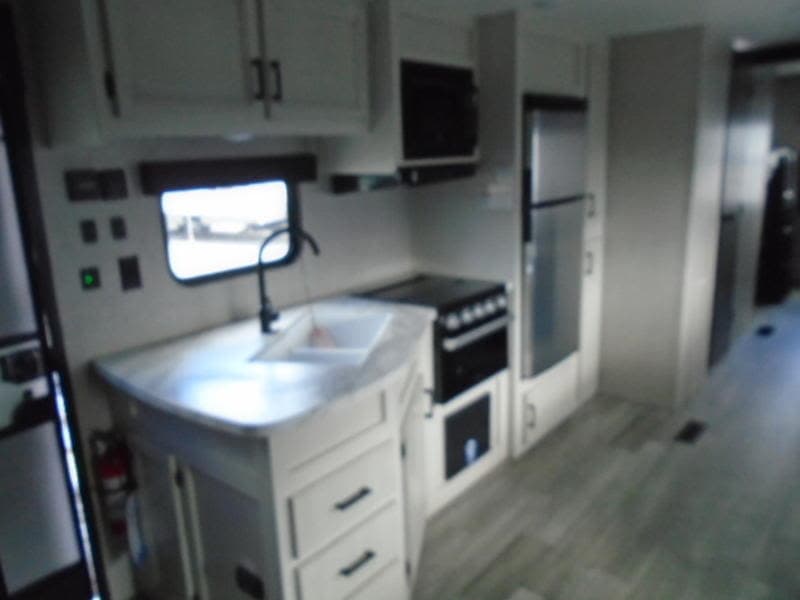 Modern RV rental kitchen with sink, stove, microwave, fridge, plus ample counter and cabinet space. Ready for your next adventure.