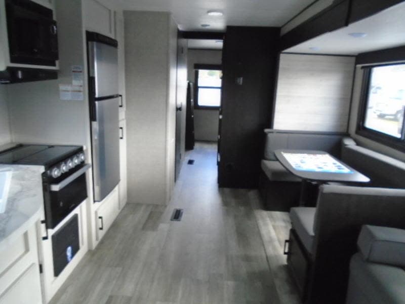 Explore this modern **RV rental** interior! Features a well-equipped kitchen, spacious hallway, and comfy dinette with window views.
