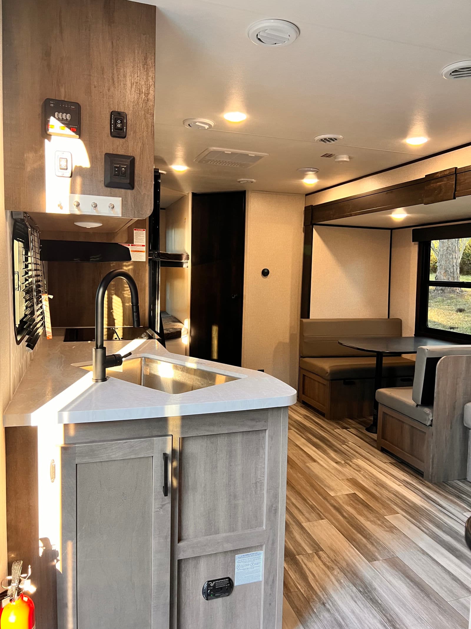 Bright rv rental interior featuring a stylish kitchen with sink, cozy dinette, and bunk area for a great travel experience.