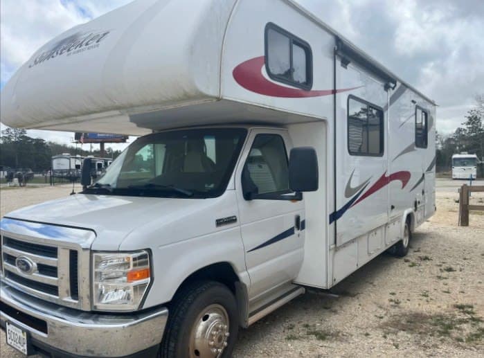 White Class C Sunseeker RV rental parked outdoors on gravel. Perfect motorhome for your next camping or travel adventure.