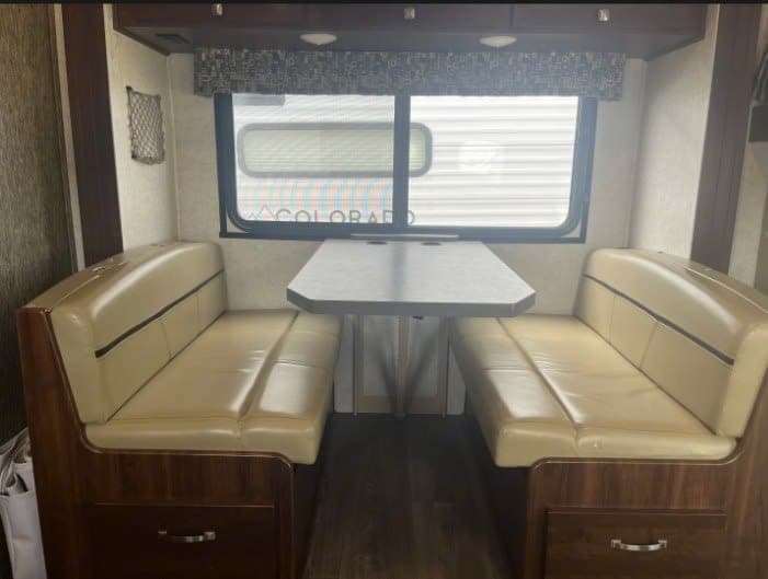 Cozy RV rental dinette with comfy bench seating and a table, perfect for meals and relaxation during your travels.
