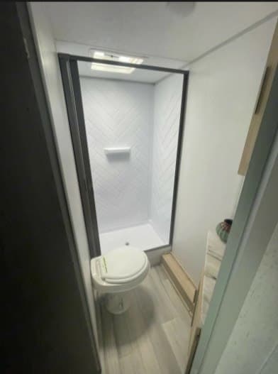 RV rental bathroom features a compact shower with herringbone walls, a toilet, and a small vanity with a decorative item.
