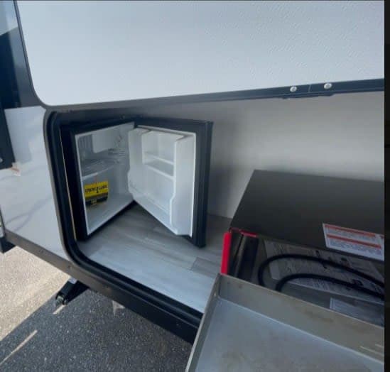 This RV rental features an exterior compartment with a mini-fridge and pull-out outdoor cooktop, great for camping.