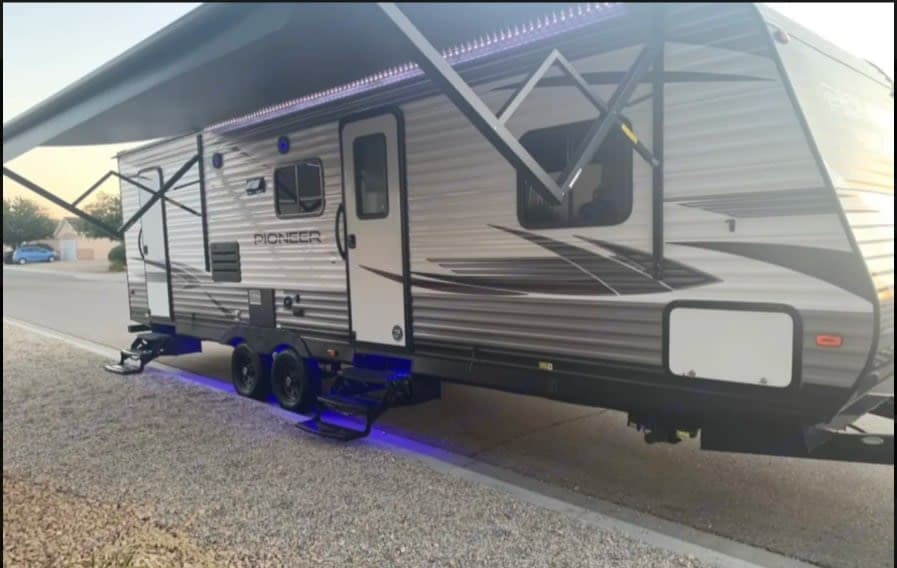 Experience adventure with this Pioneer RV rental, featuring an extended awning, LED lights, and cool blue underglow.