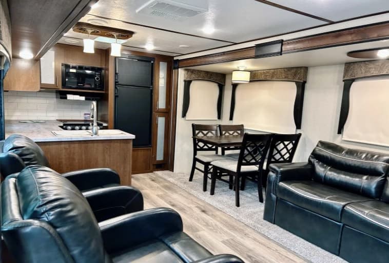 Spacious, modern RV rental interior featuring a kitchen, dining area, and comfortable living room seating.