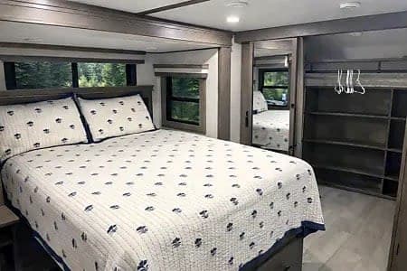 Comfortable RV rental bedroom featuring a large bed, built-in closet, and scenic window views.