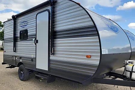 Close-up of a new gray Salem FSX travel trailer, ideal for an RV rental. Features include an awning and entry steps.