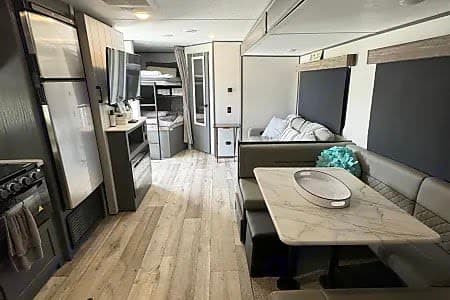 Spacious RV rental interior featuring a modern dinette, kitchenette, and hidden bunk beds for comfortable travel.