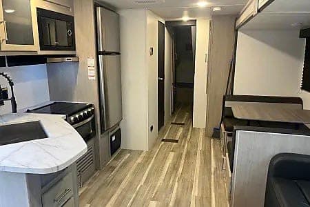 Bright rv rental interior with a modern kitchen, stainless steel fridge, and cozy dinette perfect for travel comfort.