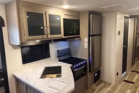 Spacious RV rental kitchen with modern appliances and light-colored cabinetry, perfect for your next travel trailer adventure.