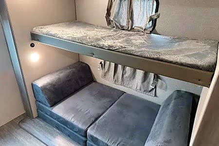 Cozy RV rental bunk beds feature a comfy top bunk and a versatile lower sofa for sleeping or lounging in your camper.