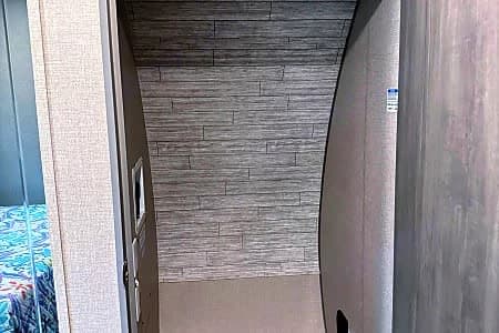 Cozy RV rental interior: A narrow passage with textured gray walls, hinting at a sleeping area. Functional RV design.