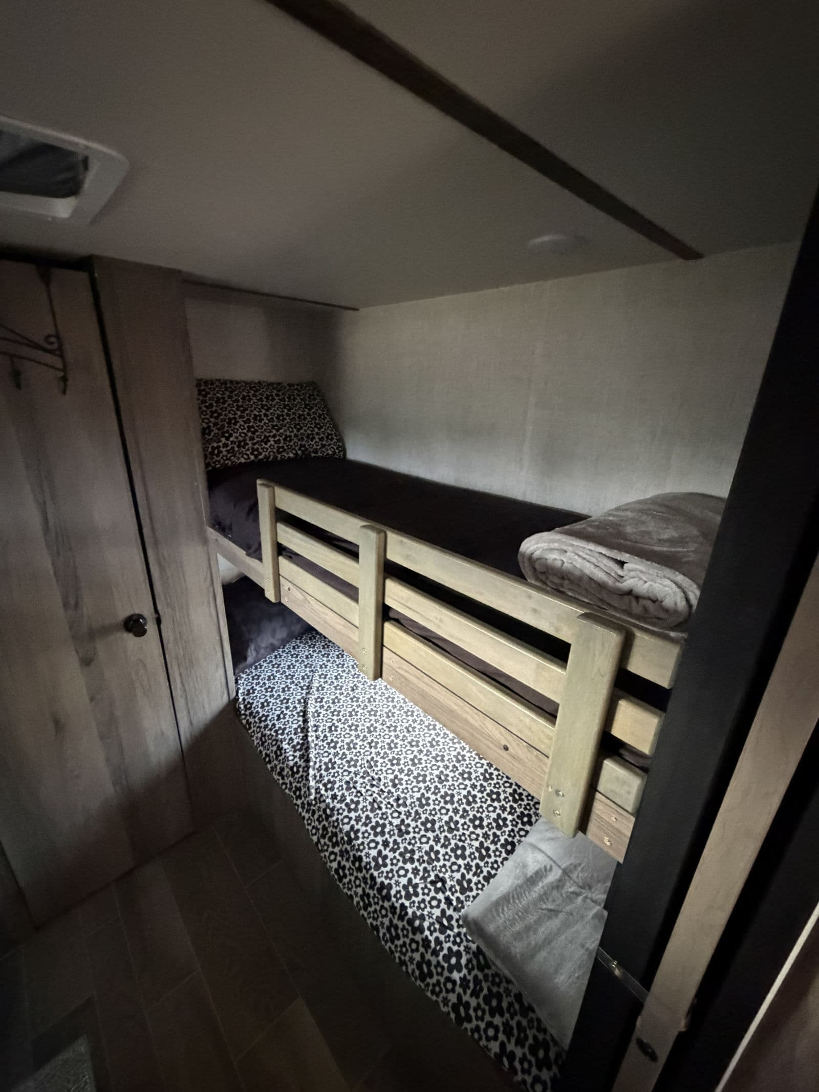 This RV rental features cozy bunk beds with patterned linens, offering a compact sleeping area for travelers.