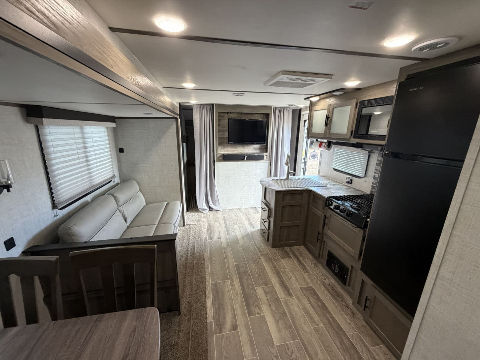 Step inside this modern RV rental: a stylish interior featuring a full kitchen, comfortable living area with sofa, and dining space.