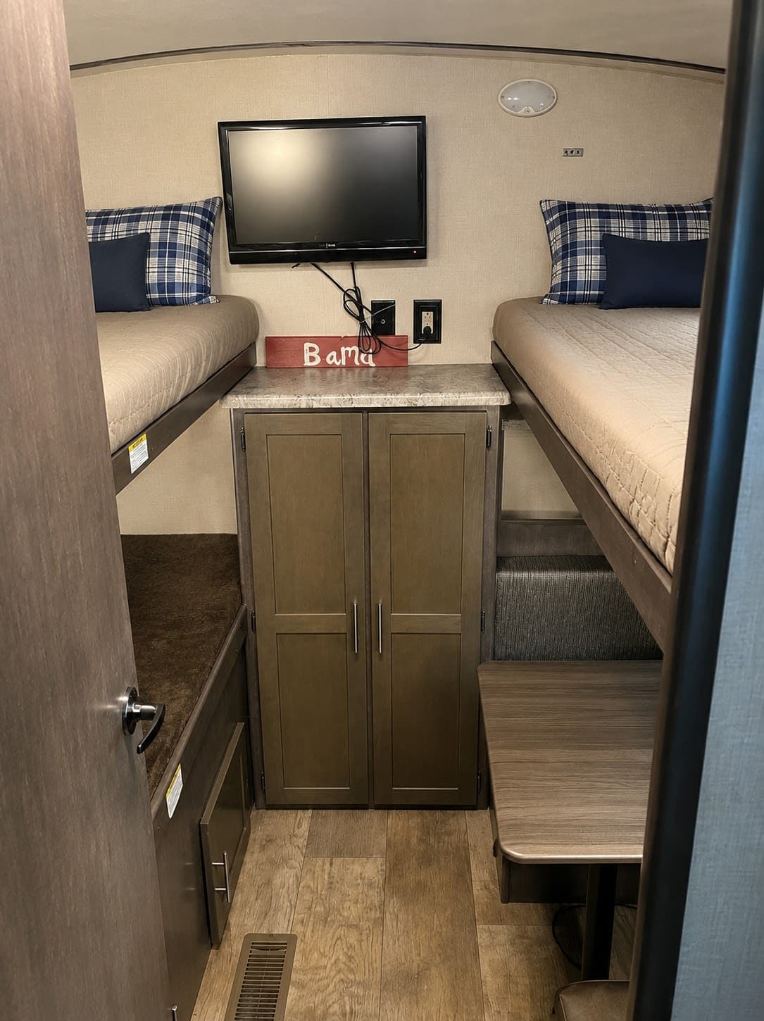 This RV rental features a cozy bunk room with twin bunk beds, a TV, storage, and dinette seating. Great for family trips!