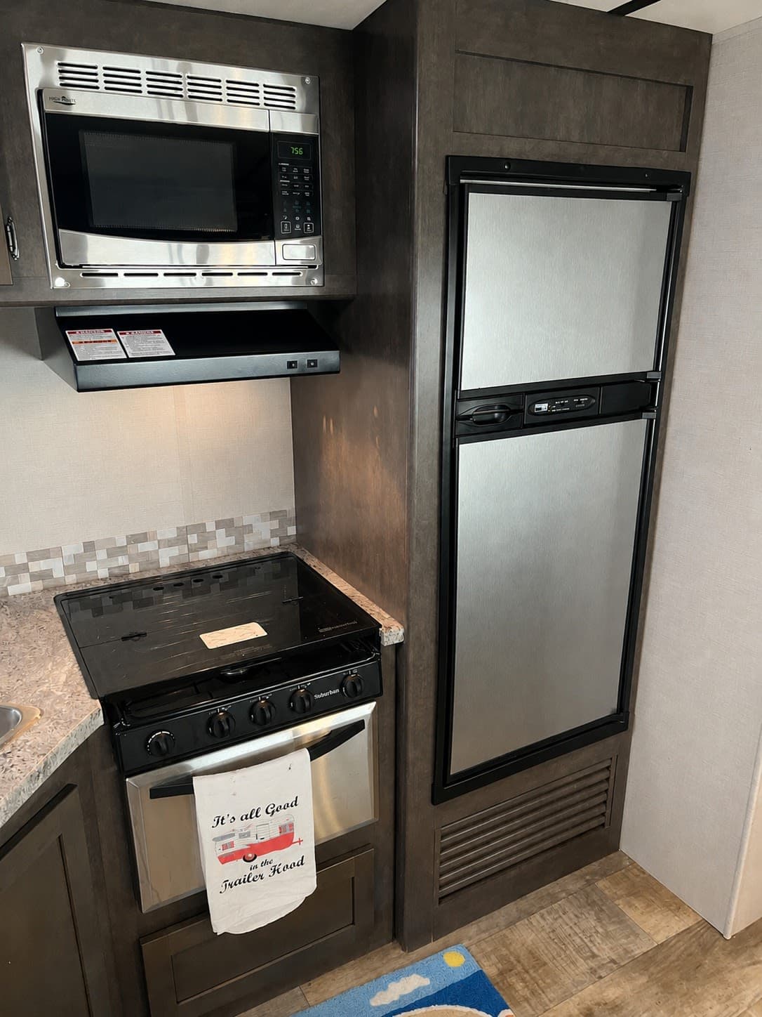 RV rental kitchen features microwave, stove, oven, and refrigerator. Essential amenities for your road trip comfort.