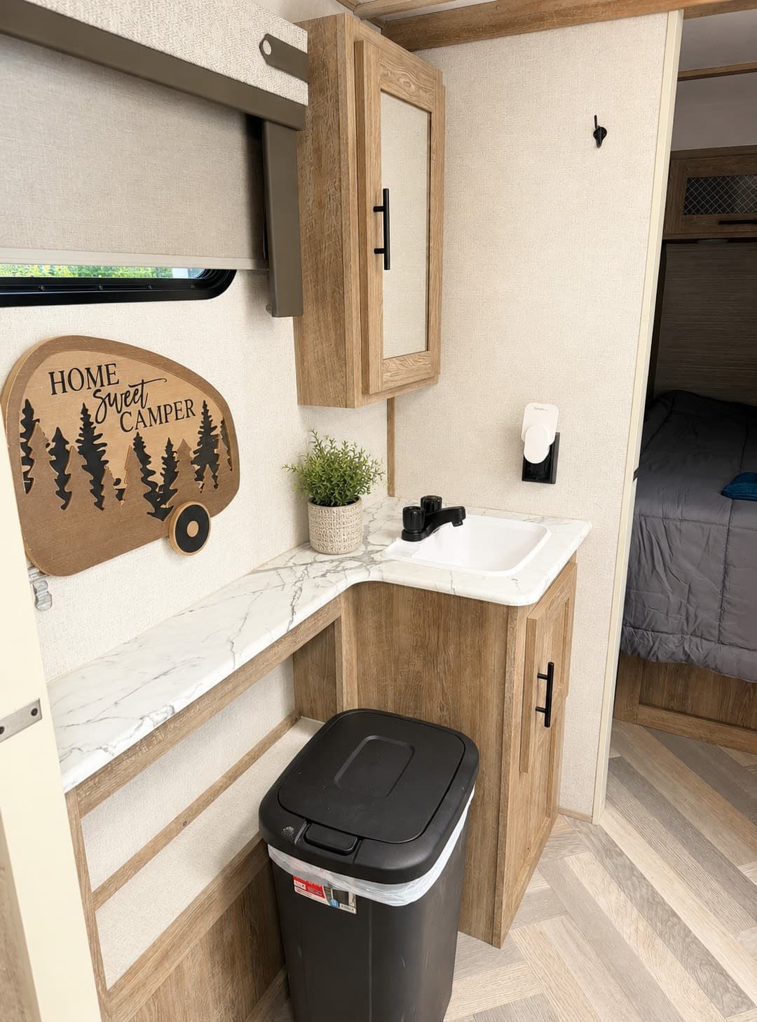 RV rental bathroom vanity area featuring a sink, mirrored cabinet, and 'Home Sweet Camper' decor. Compact and functional.