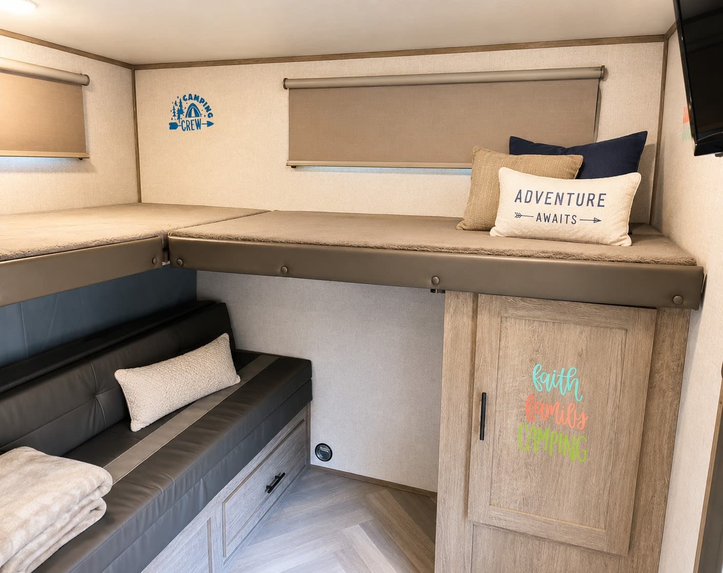 An rv rental's cozy interior, showing two bunk beds above a sofa with storage, decorated for family adventure.