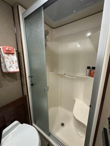 RV rental bathroom with a clean shower, toilet, and built-in seat, perfect for comfortable travels.