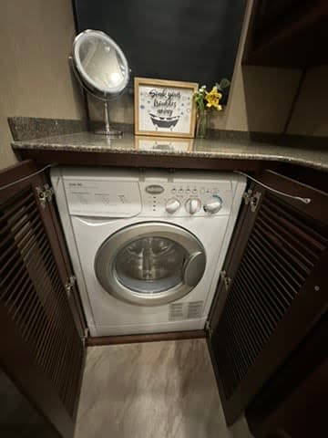 Compact front-loading washer/dryer in an RV rental cabinet, with counter space & decor. Essential laundry amenity for travel.